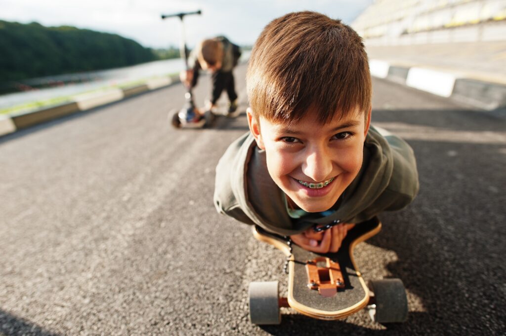 Boy with braces lying on a skateboard, close up portrait.